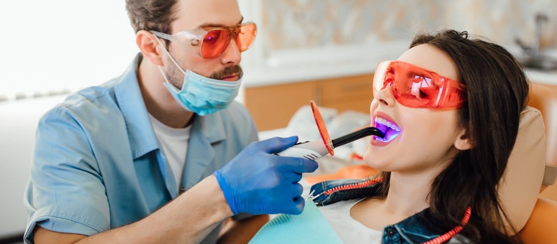 medicine-dentistry-healthcare-concept-dentist-using-dental-curing-uv-lamp-teeth-patient 2
